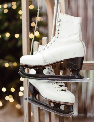 ice skates hanging on a wall in front of a lit-up tree