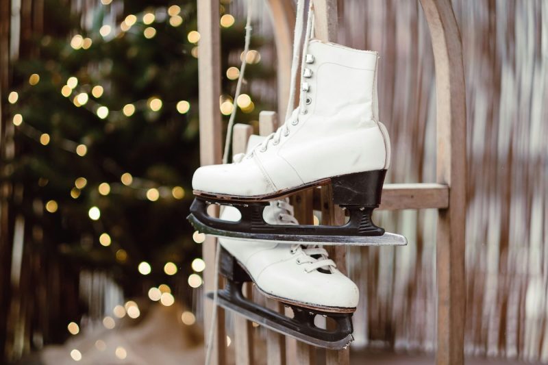 ice skates hanging on a wall in front of a lit-up tree