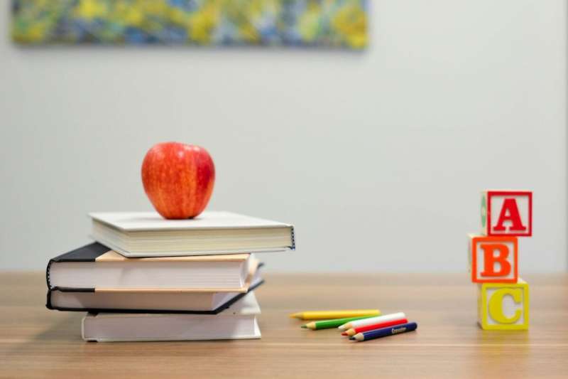 books, an apple, pencils, and ABC blocks on a desk