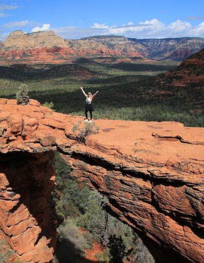 a hiker posing on top of Devil's Bridge in Sedona