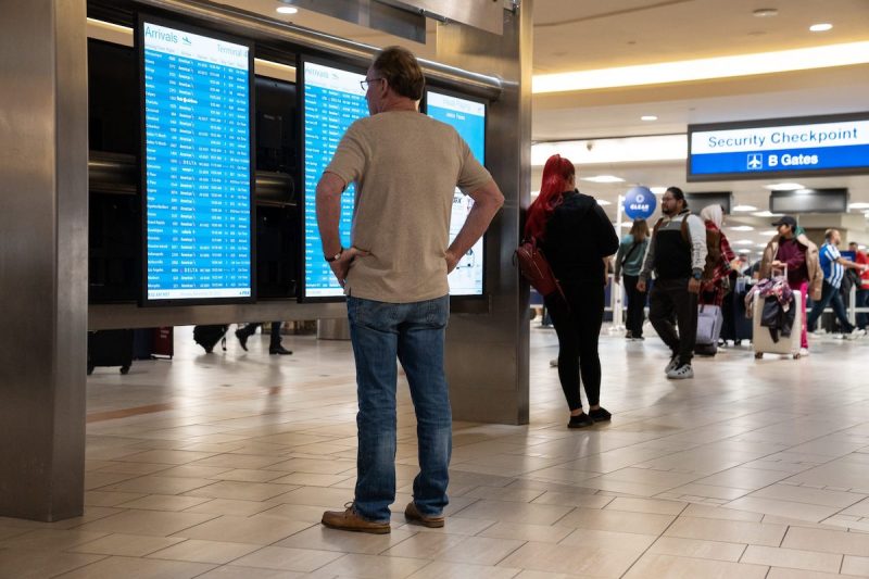 Travelers check flights on screen in airport terminal