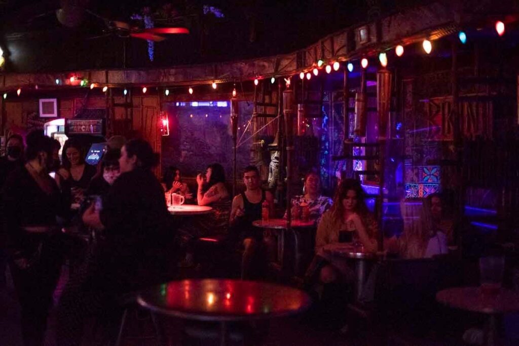 patrons drinking and sitting inside a dark dive bar