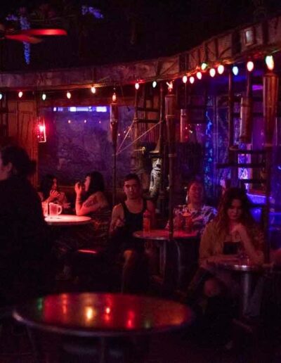 patrons drinking and sitting inside a dark dive bar