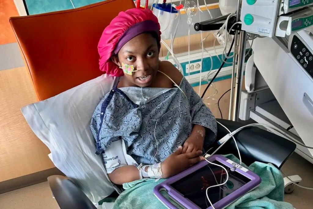 teenage girl in hospital gown sitting in hospital bed