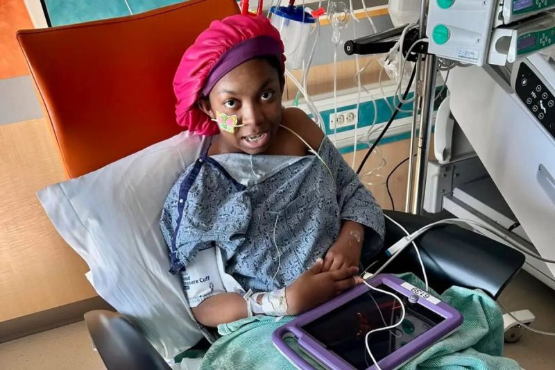 teenage girl in hospital gown sitting in hospital bed