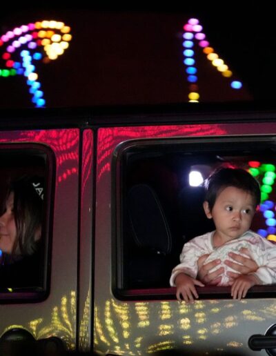 little boy looks out of car at Christmas lights