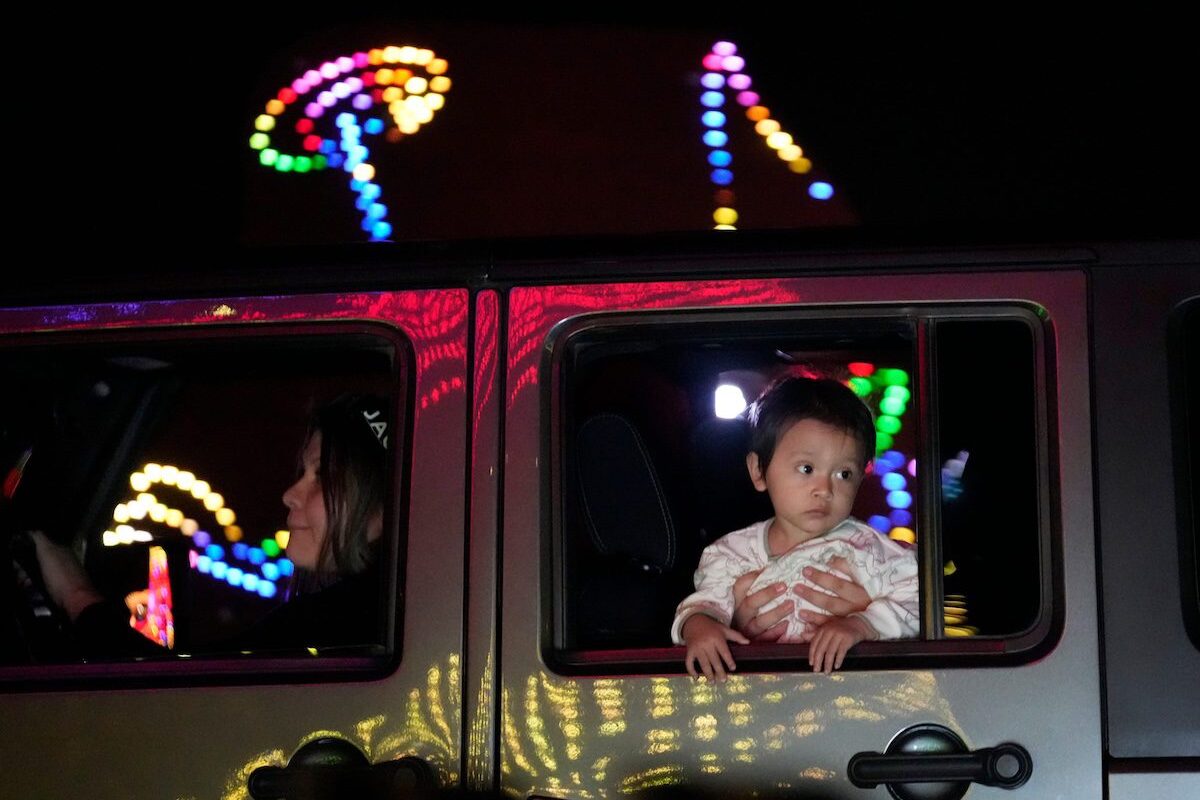 little boy looks out of car at Christmas lights