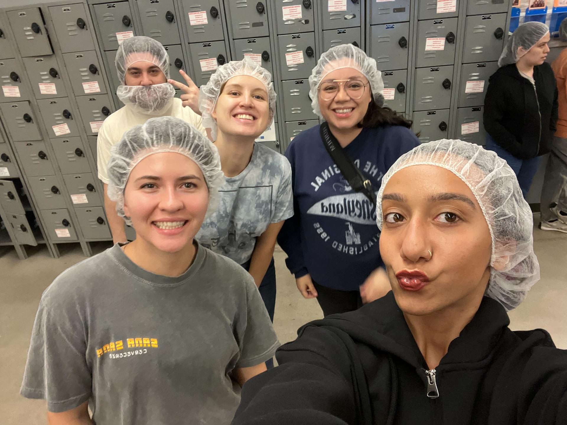 group of five people smiling in hairnets in front of lockers