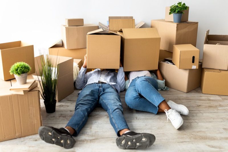 two people lying on ground with moving boxes covering their heads