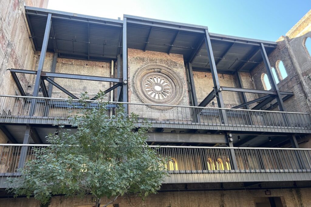 inside of a courtyard with a brick wall, rose window, and steel floors