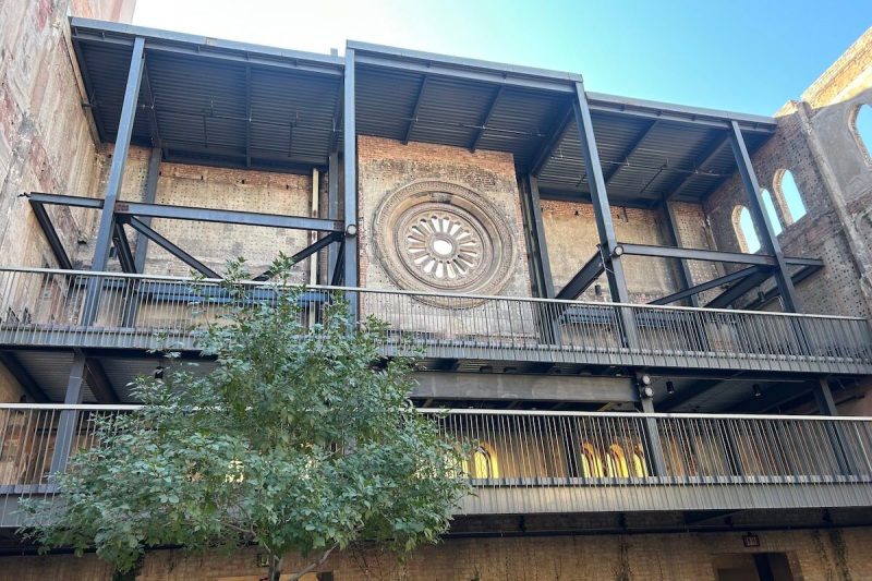 inside of a courtyard with a brick wall, rose window, and steel floors