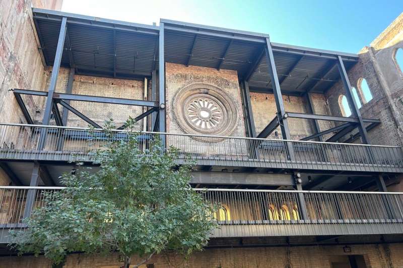 inside of a courtyard with a brick wall, rose window, and steel floors