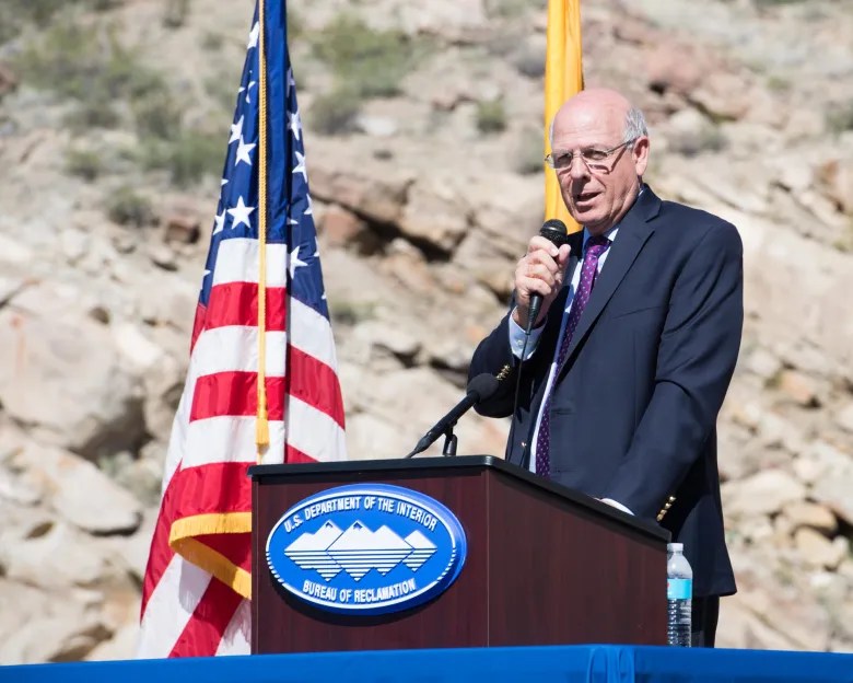 man speaking at podium outdoors
