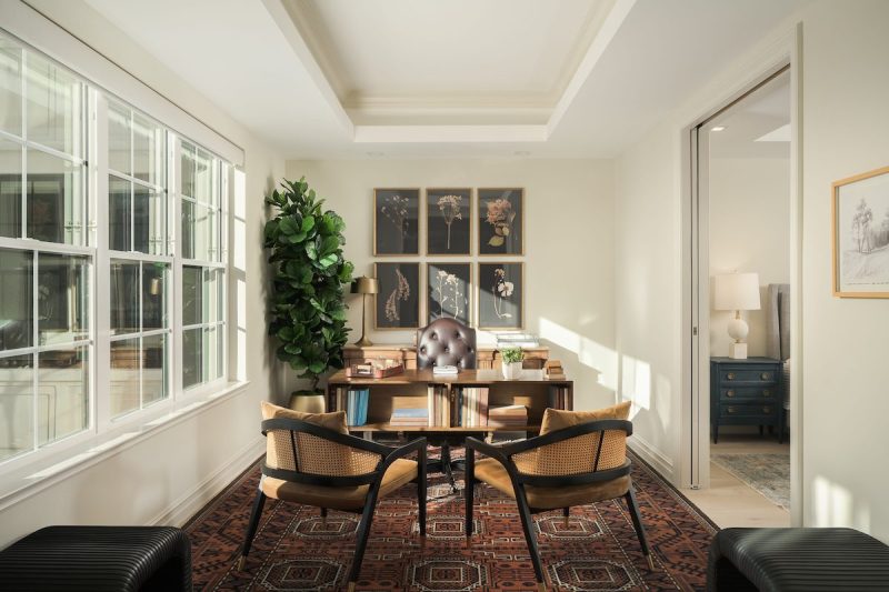 interior of an apartment room with two chairs and a bookshelf and decorations