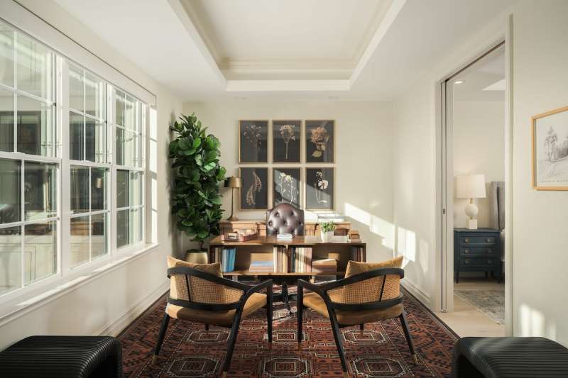 interior of an apartment room with two chairs and a bookshelf and decorations