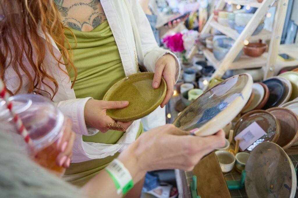 Two young women choosing ceramic plates at a flea market