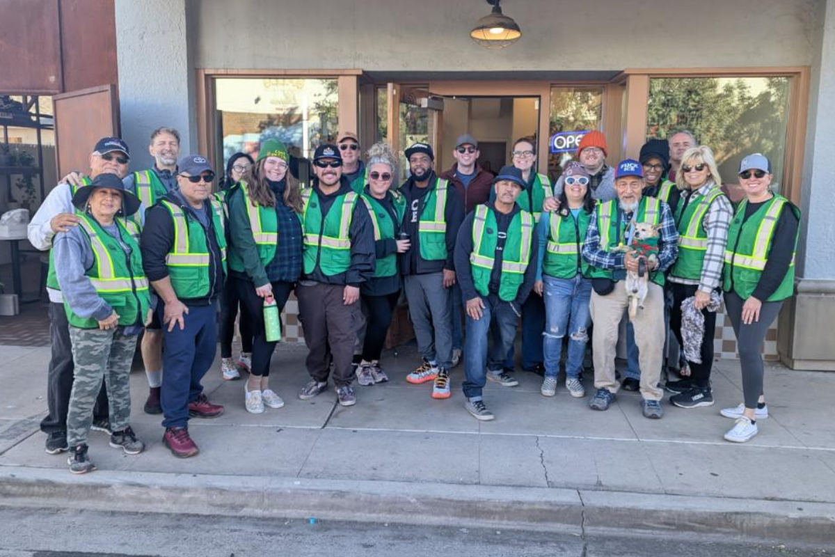 group of people in safety vests posing in front of building