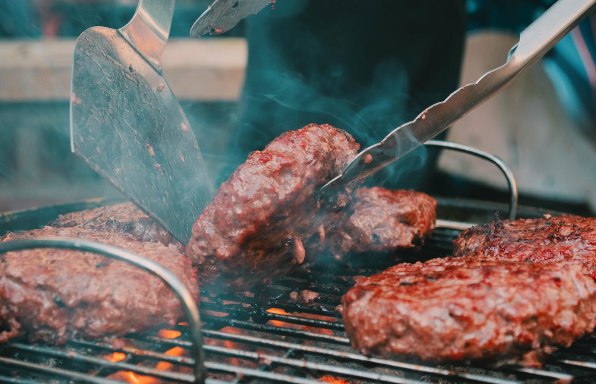 spatula flipping burgers on a smoky grill