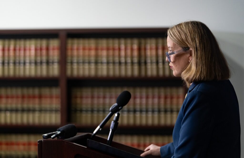 Mayes speaking into mic