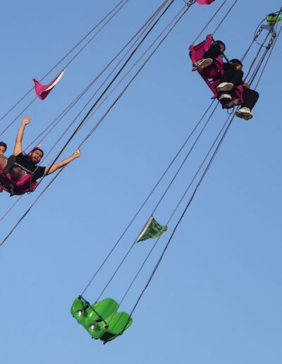 people on a swing ride against a blue sky