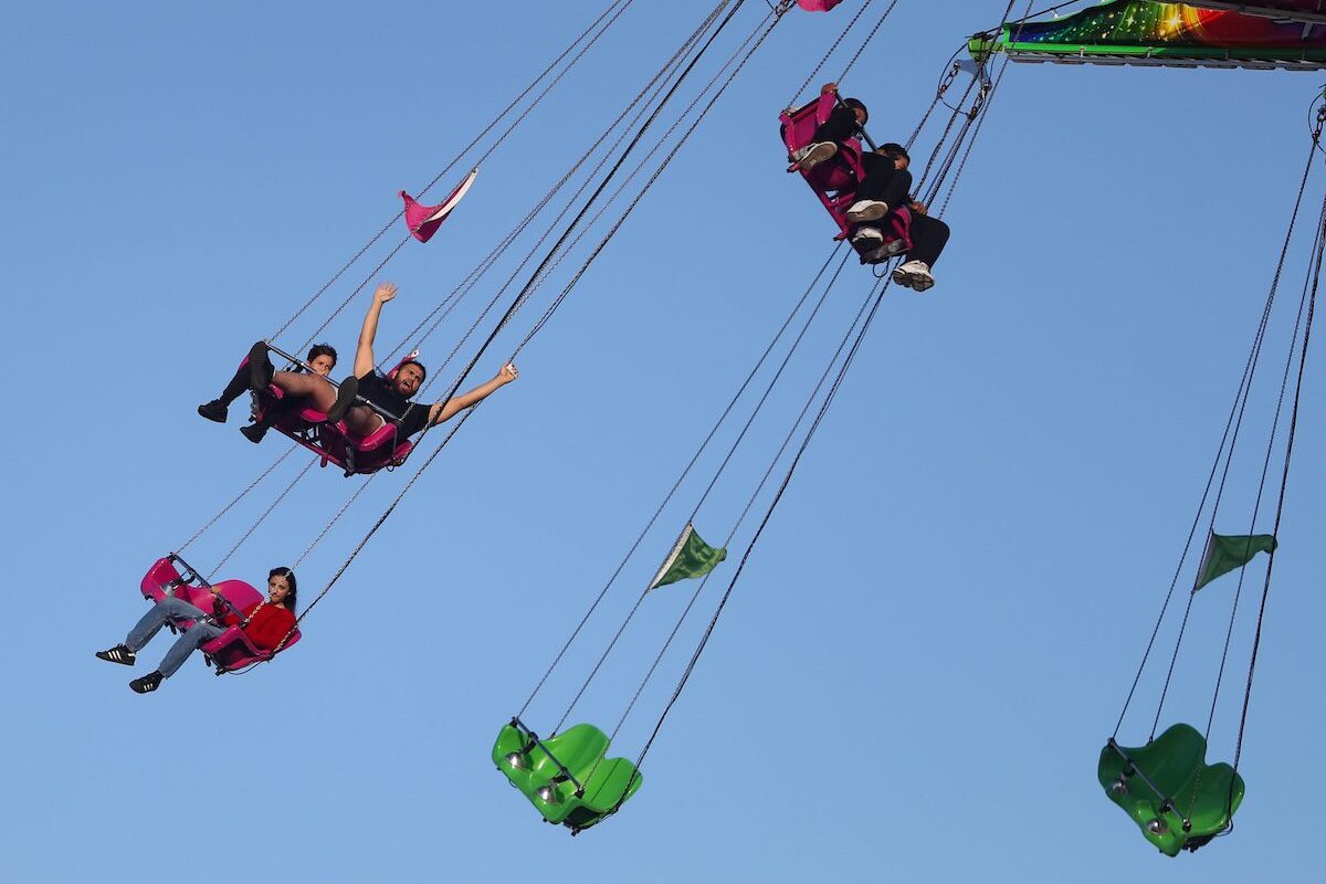 people on a swing ride against a blue sky