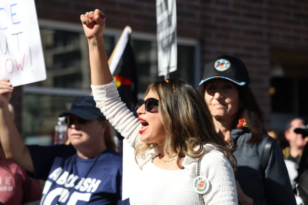 woman yells with fist raised within a crowd of protesters