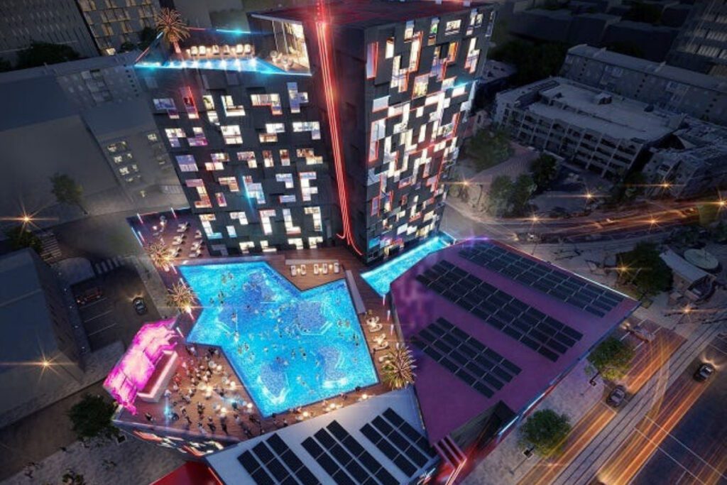 rendering of a tall hotel with a rooftop pool below lit up in colors at night