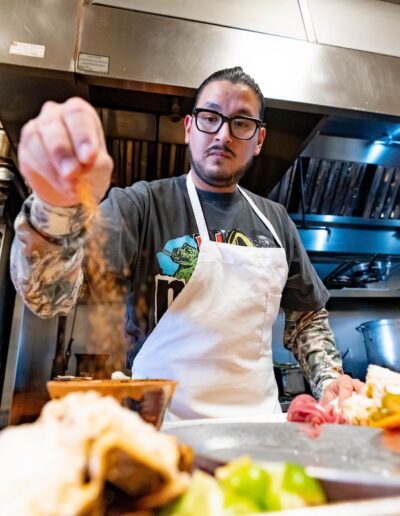 man sprinkling seasoning on a plate in a kitchen
