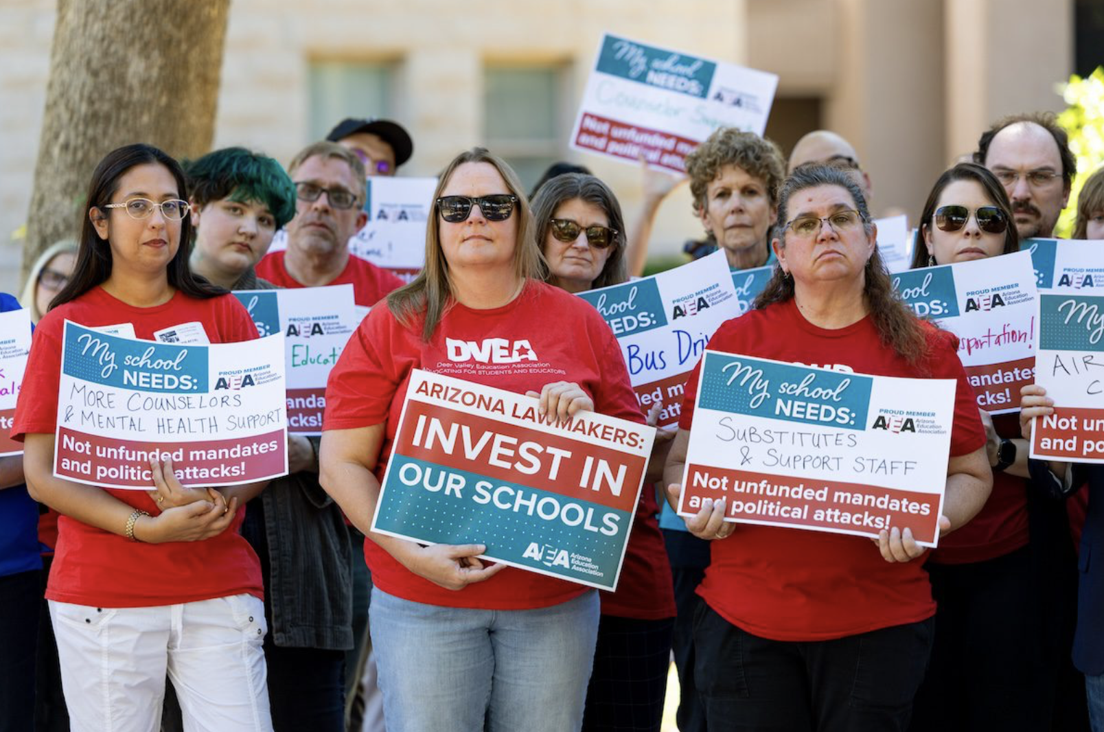 group of people holding signs asking lawmakers to invest in schools