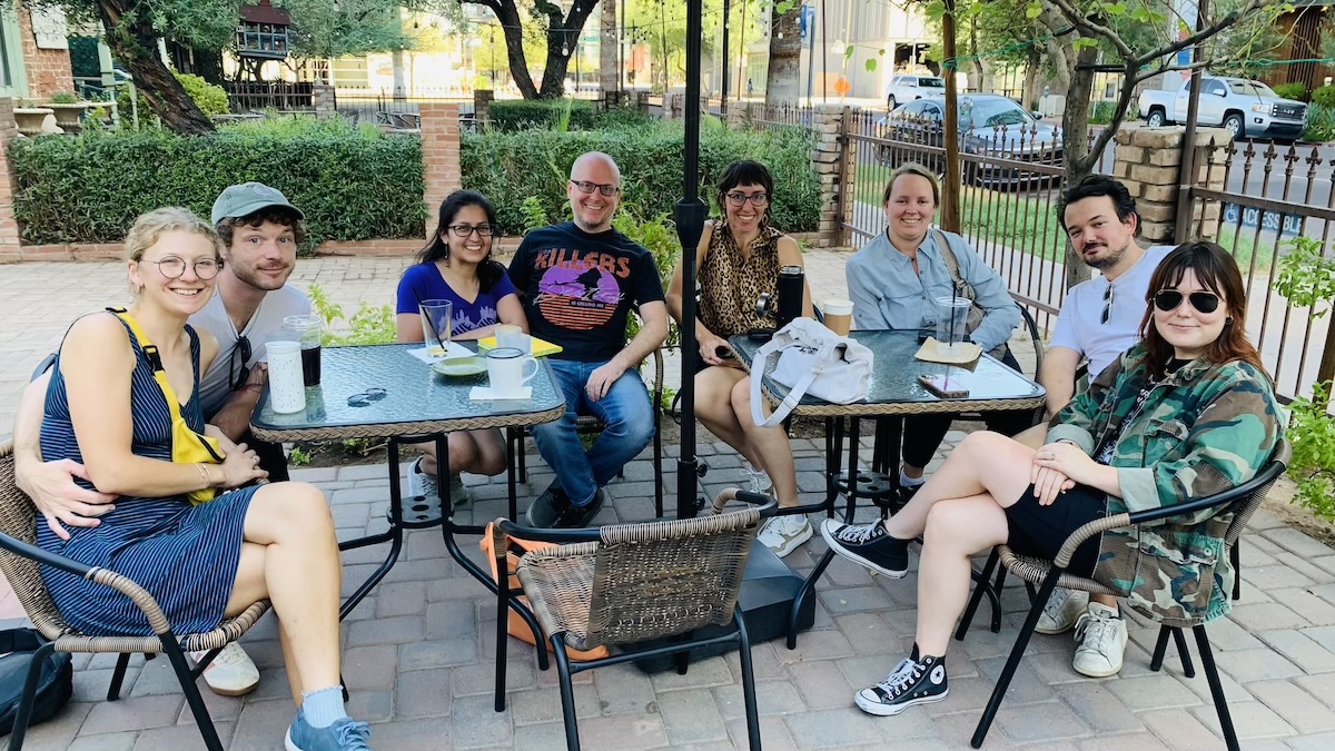 eight people seated around a patio table smiling for camera