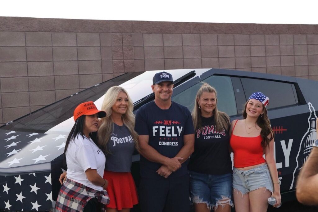group of people posing in front of a Cybertruck