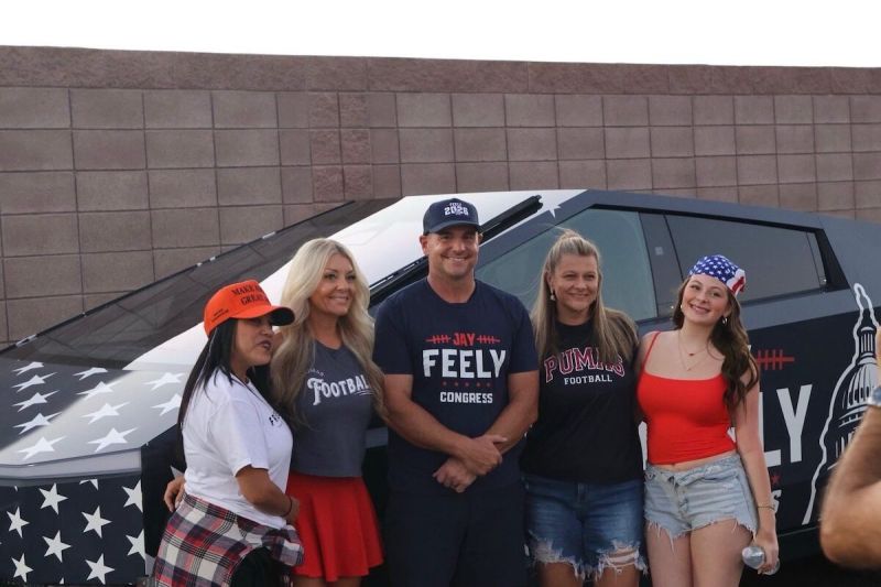 group of people posing in front of a Cybertruck