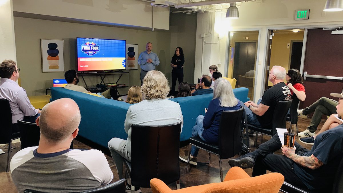 a man gives a presentation to people seated around a room