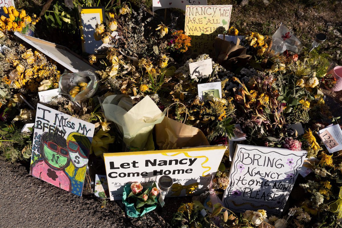 a collection of signs and flowers in support of Nancy Guthrie's return