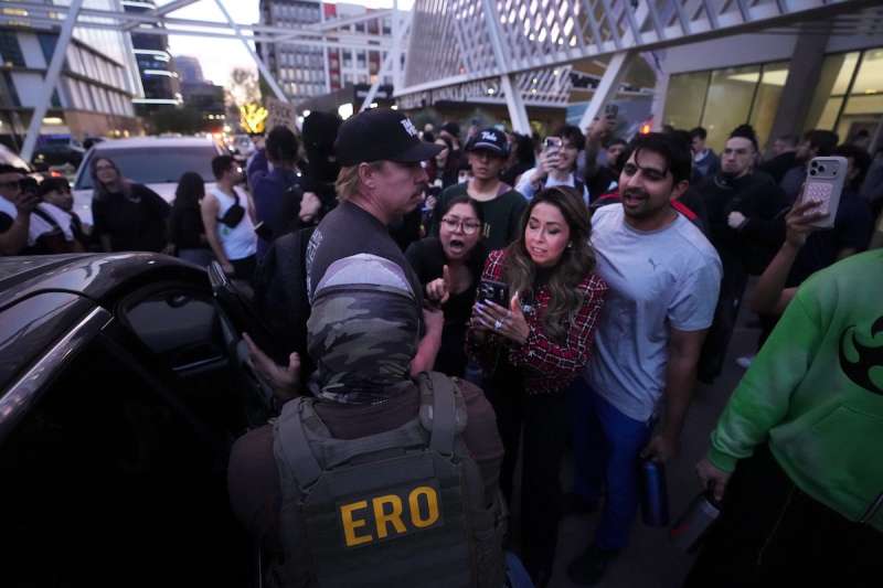 protestors crowding ice agents outside a building and car
