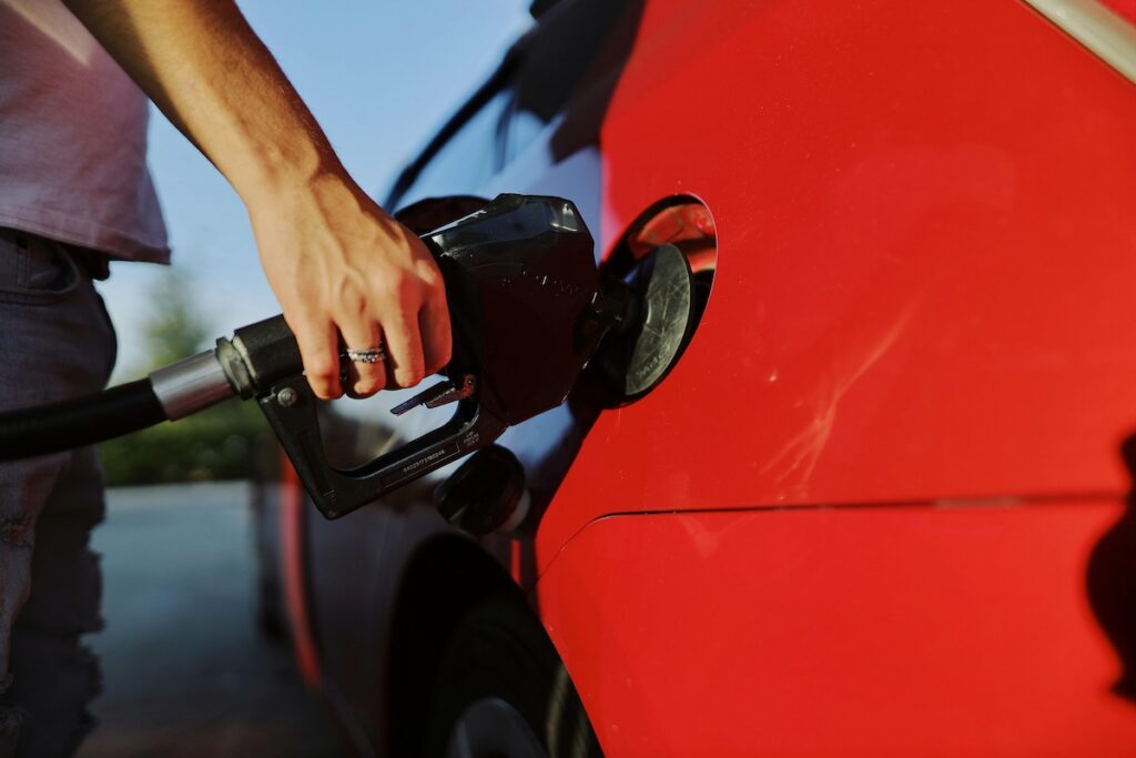 hand holding gas pump in a car's gas tank
