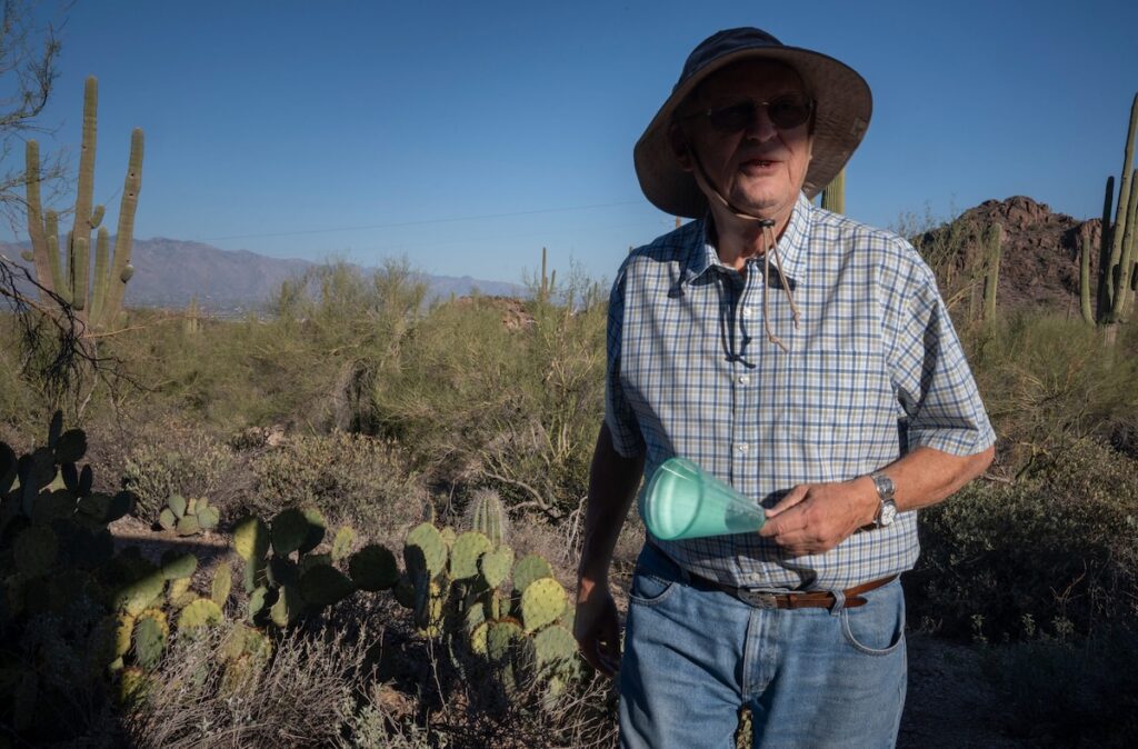 man standing in desert holding a blue funnel