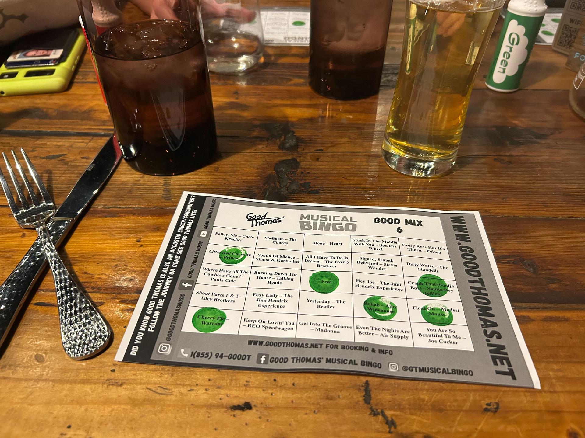 a paper on a table divided into bingo squares with some squares marked off with green circles of ink