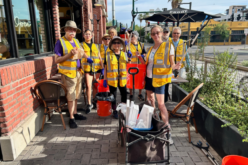 group of people in matching safety vests standing on sidewalk