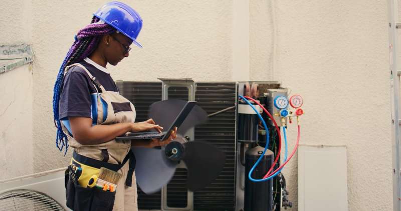 woman wearing protective gear looking at an AC unit