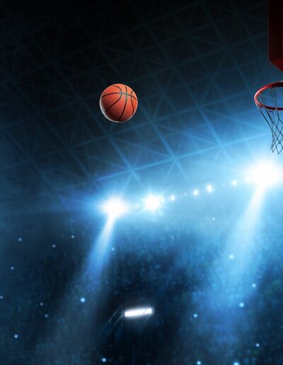 dark arena lit up with blue lights, basketball moving in arc toward hoop