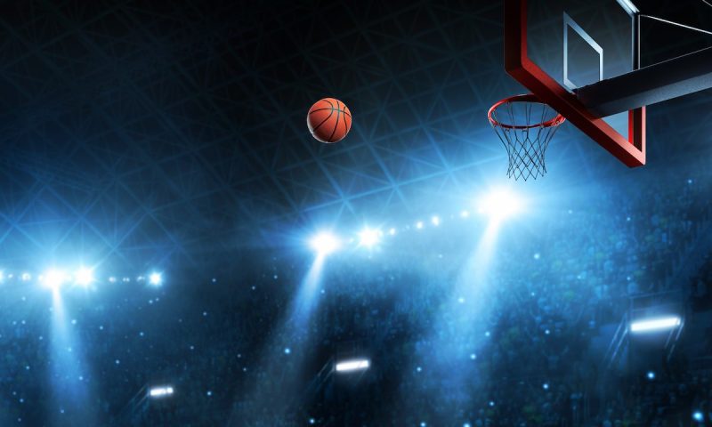 dark arena lit up with blue lights, basketball moving in arc toward hoop