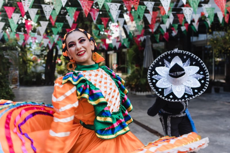 woman and boy in Mexican traditional dress in a street under banner of red, green, and white triangles