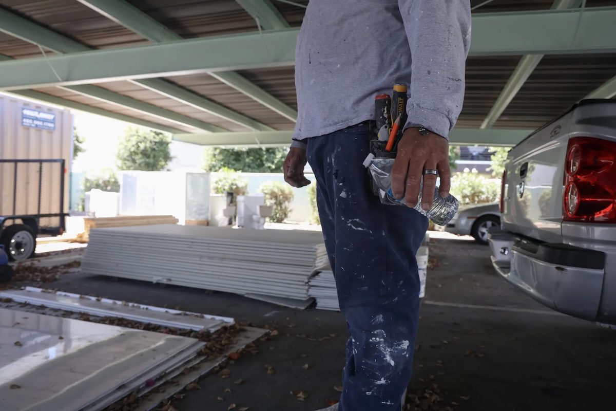 worker's torso and legs, holding a water bottle standing in a parking lot