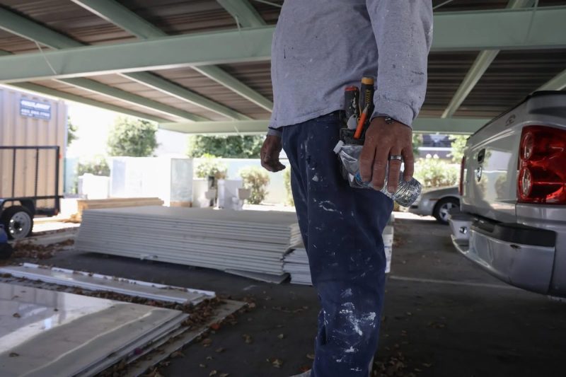 worker's torso and legs, holding a water bottle standing in a parking lot