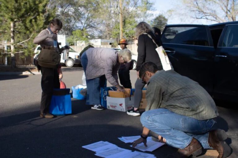 a group of people sorting papers on the ground and looking through boxes