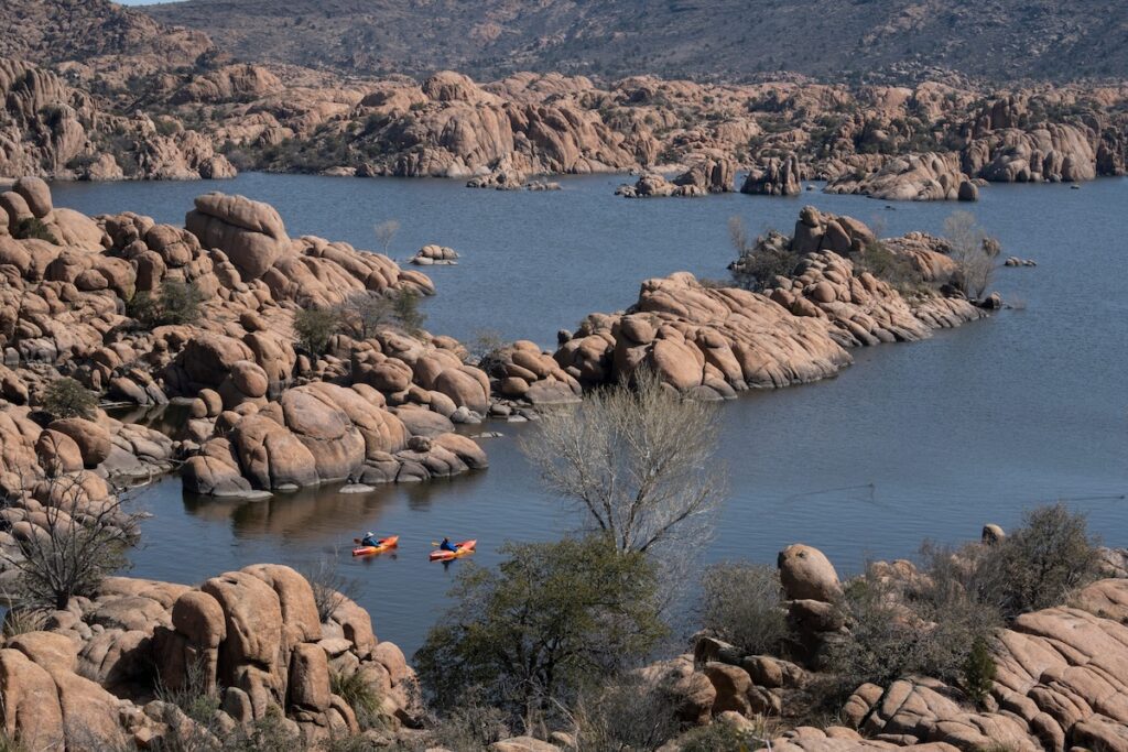 aerial view of a lake with rock formations, and kayakers moving through the water