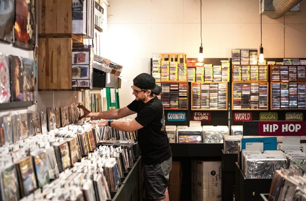 man flipping through a stack of records in a record store