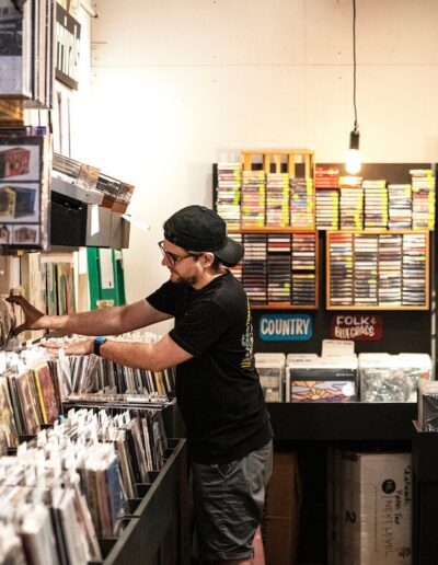 man flipping through a stack of records in a record store