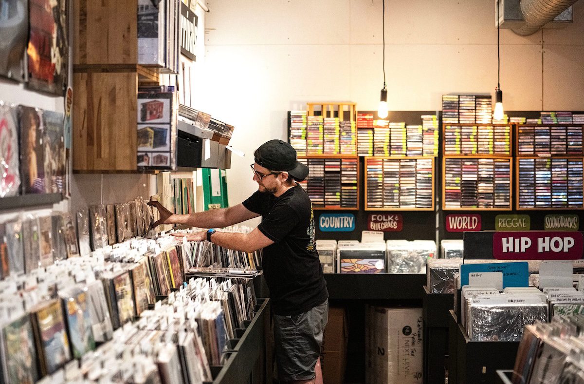 man flipping through a stack of records in a record store